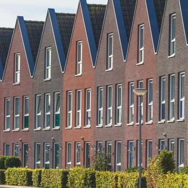 Moderne Reihenhäuser in Backstein-Optik mit spitzen Dachgiebeln.